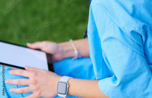 Woman doctor using tablet computer while sitting on grass.Healthcare, insurance and medicine concept