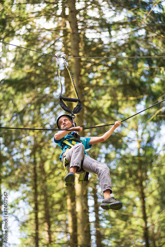 A boy pulls himself up by a rope in a high rope park