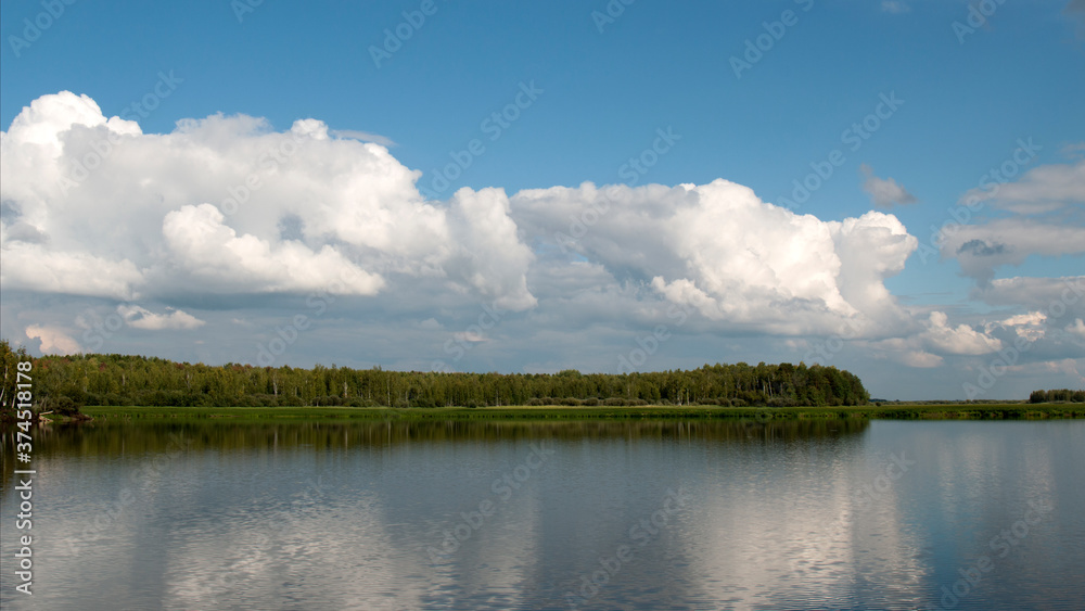 Forest lake view, smooth surface of a lake with clouds reflected, shining level of a forest lake