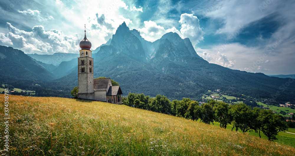 Splendid summer nature landscape. Panoramic view of idyllic mountain scenery in Alps with fresh green meadows in bloom on a beautiful sunny day in summer. famous San Valentino Church. Dolomite Alps Splendid summer nature landscape. Panoramic view of idyllic mountain scenery in Alps with fresh green meadows in bloom on a beautiful sunny day in summer. famous San Valentino Church. Dolomite Alps