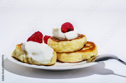 Delicious and healthy cheesecakes with sour cream and raspberries, with a Cup of black coffee. 