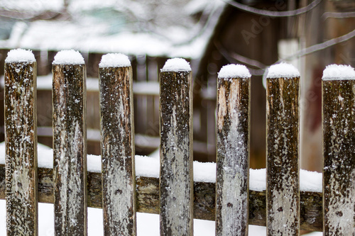 Texture of weathered wooden wall. Falling snow, in winter. Aged wooden plank fence of vertical flat boards