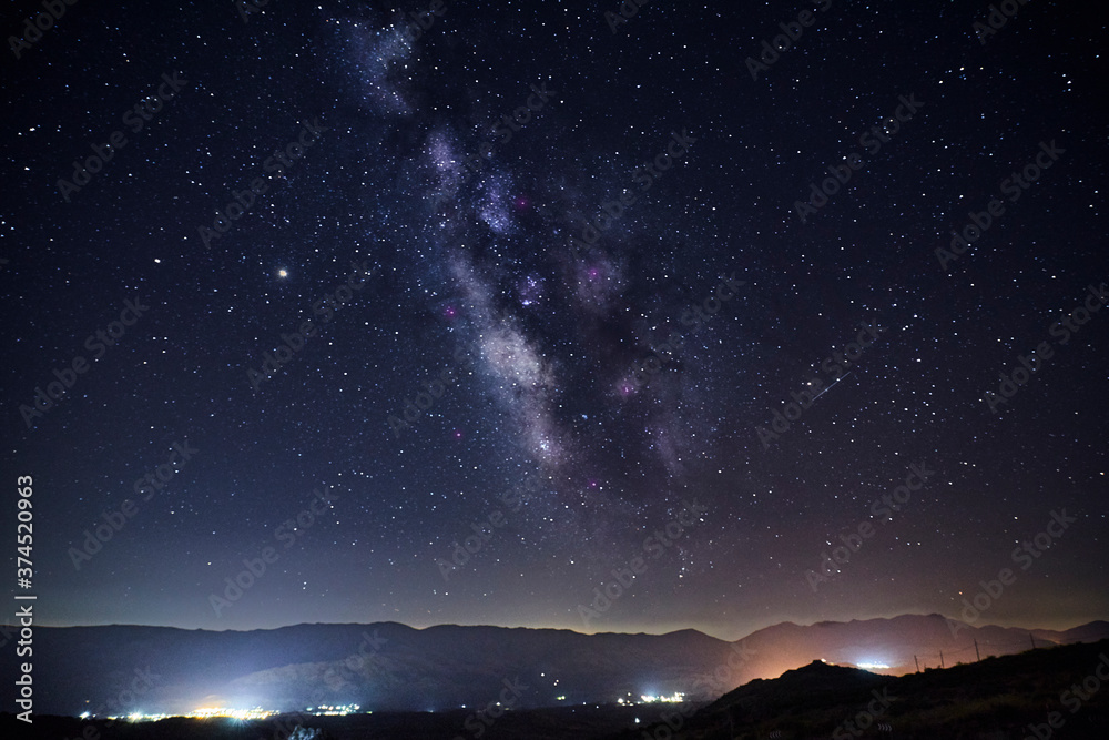 The Milky Way galaxy over the mountains and lights of some villages