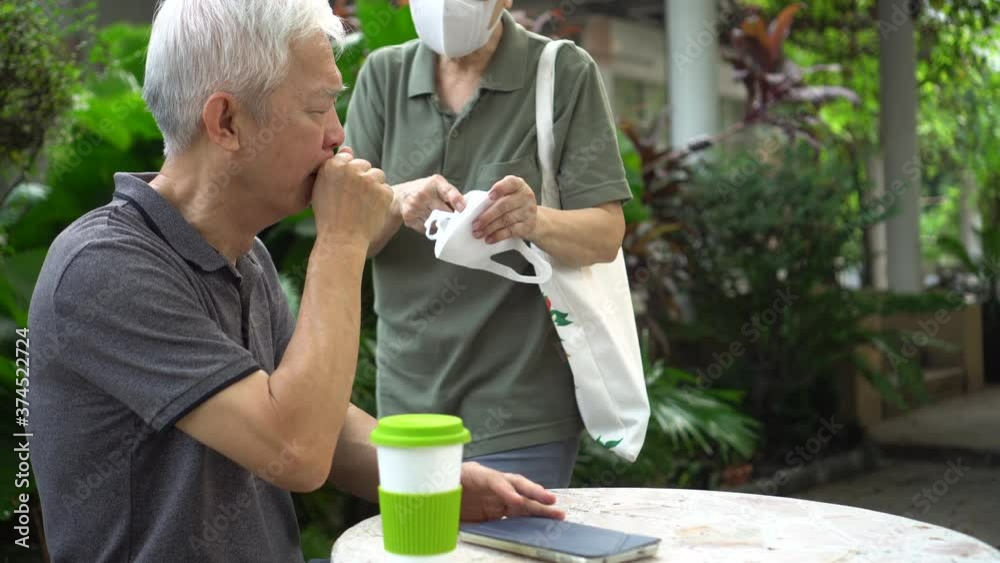 Asian elder senior couple wife give mask for husband to wear during pandemic covid sesitive time Asian elder senior couple wife give mask for husband to wear during pandemic covid sesitive time