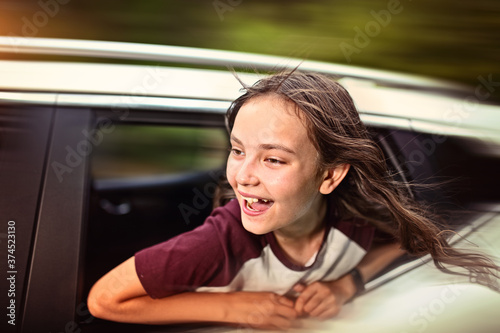 smiling brunette teenage girl is driving the car