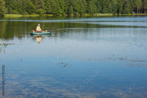 A fisherman on a rubber boat catches a fish on the lake
