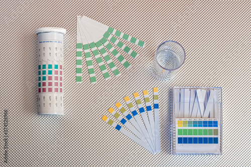 water analysis kit, ph test strips and total hardness test strips and a test tube with water on a rough metal base background