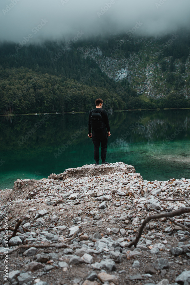 A tavel nature hiking man standing at a crystal clear mountain lake. Exploring the mountains. Gosauseen, Gosau, Austrian Alps, Salzkammergut in Austria, Europe A tavel nature hiking man standing at a crystal clear mountain lake. Exploring the mountains. Gosauseen, Gosau, Austrian Alps, Salzkammergut in Austria, Europe