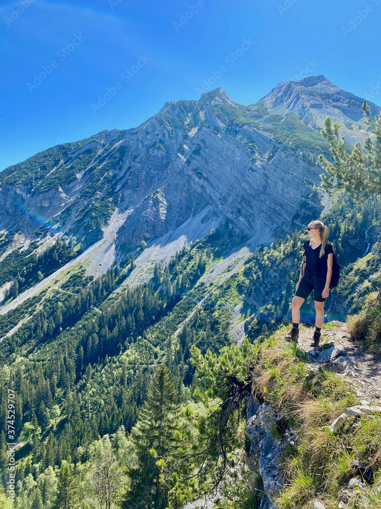 Woman looking over valley in alps, mountain view with blue sky, Bavaria, Germany