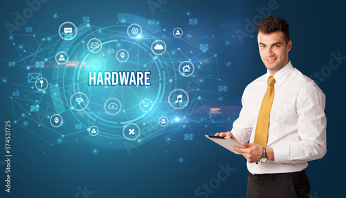 Businessman thinking in front of technology related icons and HARDWARE inscription  modern technology concept
