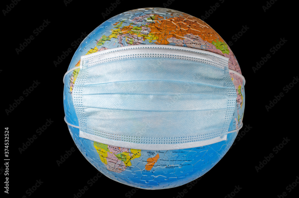 A surgical face mask putting on a world globe protecting the world from pollution and infectious diseases (closeup, isolated on black background)