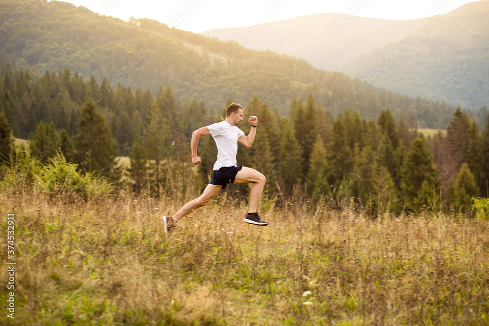 Fototapeta premium Running fitness man sprinting outdoors with beautiful mountains landscape on background. Runner training for marathon.