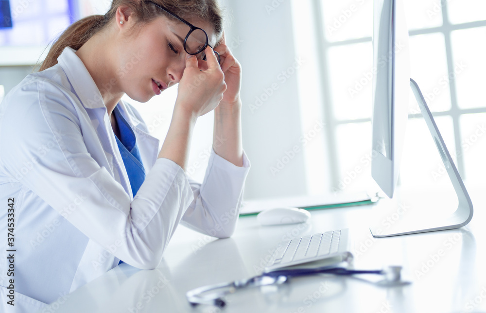 Portrait of a young female doctor suffering from a headache at work