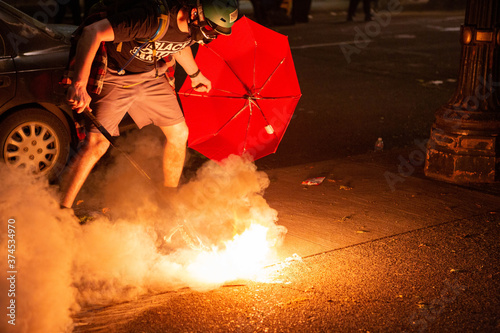 Black Lives Matter Protester tries to catch and throw back a tear gas canister with a lacrosse stick.