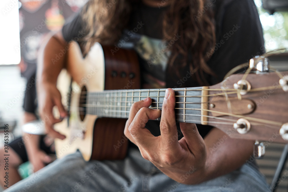 Fototapeta premium Man With Long Hair Playing Guitar. Selective focus on Hand Playing Chords.