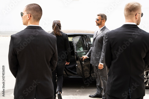 Bodyguards Protecting Businesswoman Opening Car Door photo