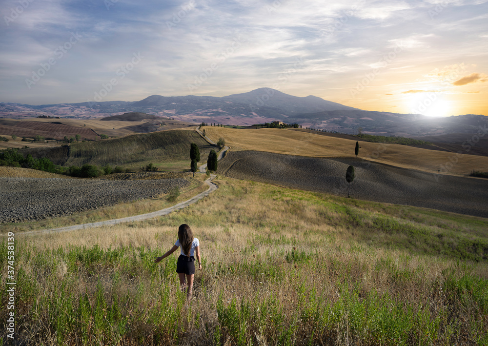 Woman on wheat field near Pienza, Val D'Orcia of Tuscany in Italy