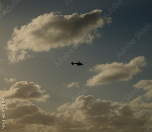 Silhouette of a helicopter flying across dark sky. Dark tone, low key, square crop.