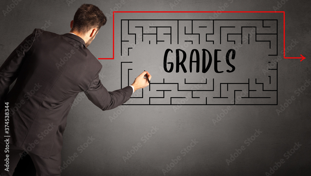 businessman drawing maze with GRADES inscription, business education concept businessman drawing maze with GRADES inscription, business education concept