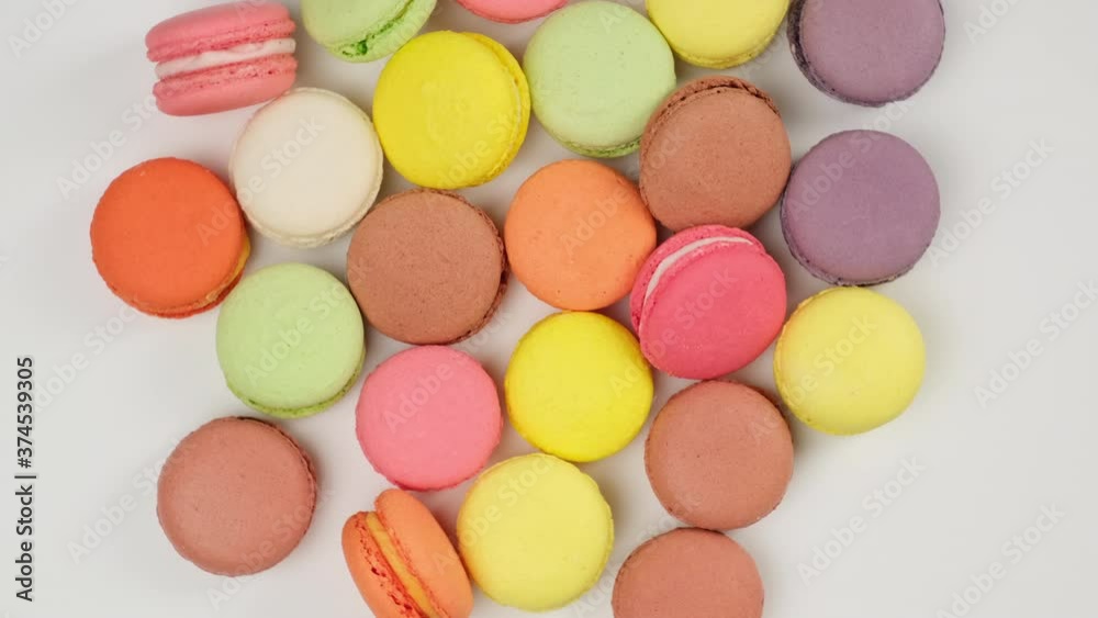 round baked multi-colored almond flour cakes macarons, dessert on a white background, sweets are spinning round baked multi-colored almond flour cakes macarons, dessert on a white background, sweets are spinning