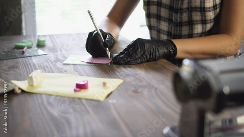 Artisan cuts polymer clay by cutter. Master works by knife in workshop.