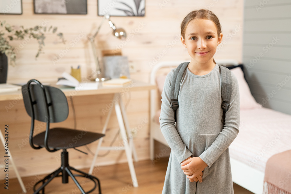 Contemporary happy schoolgirl in grey dress standing in front of camera Contemporary happy schoolgirl in grey dress standing in front of camera