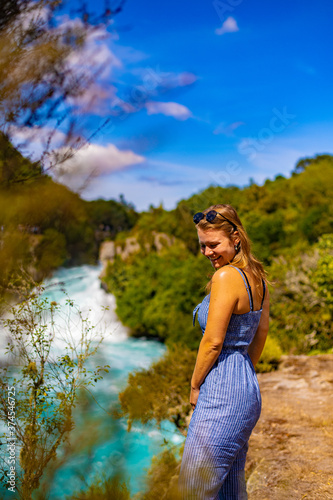 young woman in sunglasses in front of a waterfallw