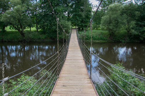 Fototapeta Naklejka Na Ścianę i Meble -  Chain bridge with a wooden floor across the river