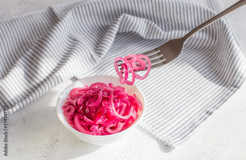 Juicy red onion marinated in lemon juice on a light background.