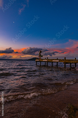 silhouette of a woman on a pier at the beach at sunset