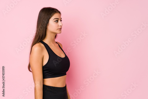 Young caucasian fitness woman doing sport isolated gazing left, sideways pose.