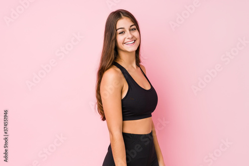 Young caucasian fitness woman doing sport isolated looks aside smiling, cheerful and pleasant.