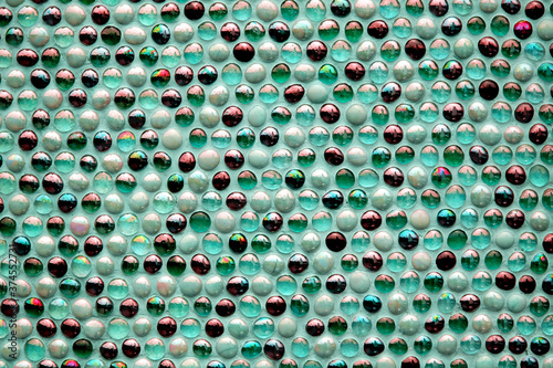Glass balls and plaster wall decoration with translucent backlit background functioning as a lamp area, filtered flash light, turquoise light on, close detail.