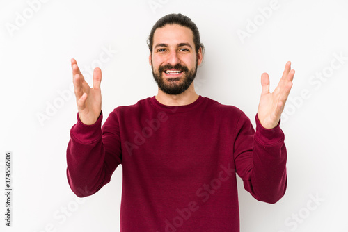 Young long hair man isolated on a white background receiving a pleasant surprise, excited and raising hands.