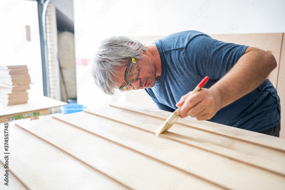 Carpenter applying varnish to the furniture he is building.