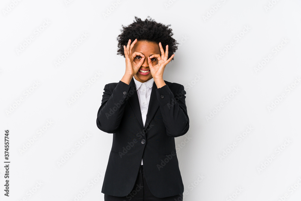 Middle aged african american business woman against a white background isolated showing okay sign over eyes Middle aged african american business woman against a white background isolated showing okay sign over eyes
