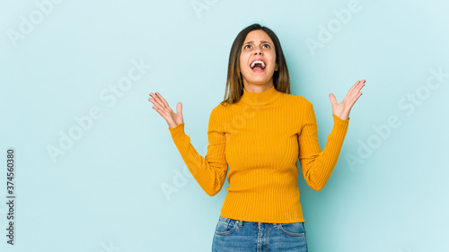 Young woman isolated on blue background screaming to the sky, looking up, frustrated.