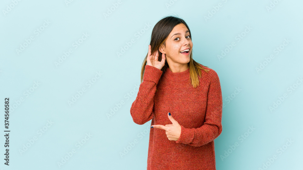 Young woman isolated on blue background trying to listening a gossip. Young woman isolated on blue background trying to listening a gossip.