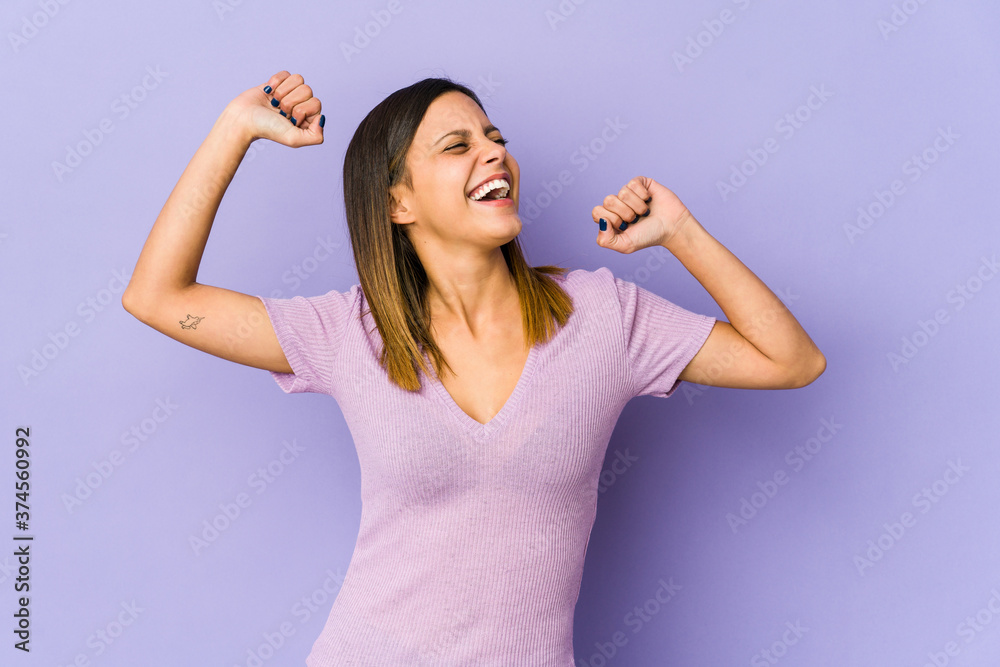 Young woman isolated on purple background raising fist after a victory, winner concept.