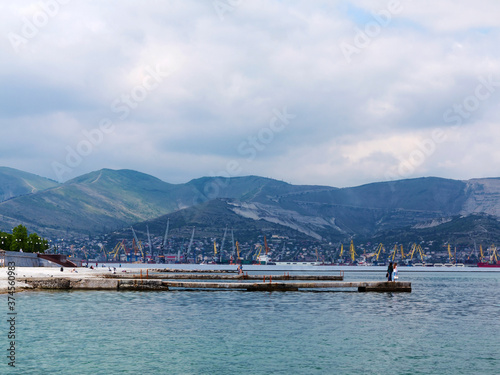 Silhouettes of city buildings and seaport on the sea coast. Novorossiysk, Russia. © Elena