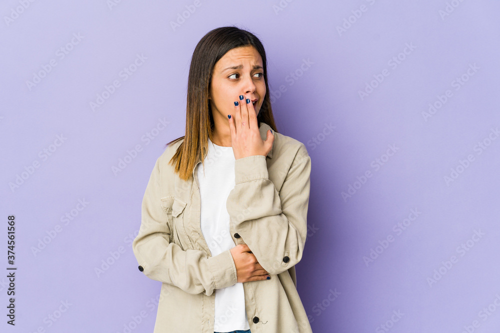 Young woman isolated on purple background yawning showing a tired gesture covering mouth with hand. Young woman isolated on purple background yawning showing a tired gesture covering mouth with hand.