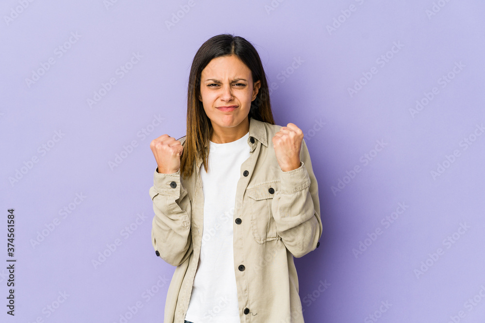 Young woman isolated on purple background showing fist to camera, aggressive facial expression. Young woman isolated on purple background showing fist to camera, aggressive facial expression.