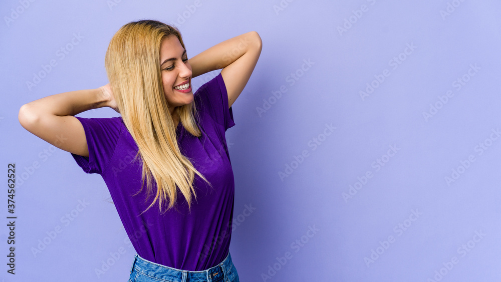 Young blonde woman isolated on purple background stretching arms, relaxed position. Young blonde woman isolated on purple background stretching arms, relaxed position.