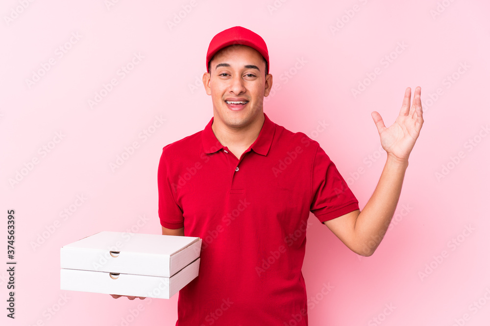 Young pizza delivery latin man isolated receiving a pleasant surprise, excited and raising hands. Young pizza delivery latin man isolated receiving a pleasant surprise, excited and raising hands.