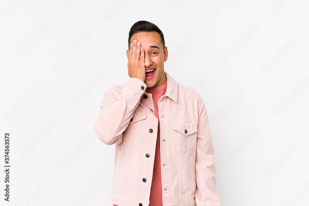 Young latin man posing isolated having fun covering half of face with palm. Young latin man posing isolated having fun covering half of face with palm.