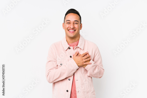 Young latin man posing isolated laughing keeping hands on heart, concept of happiness.