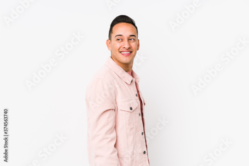 Young latin man posing isolated looks aside smiling, cheerful and pleasant.