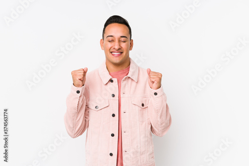 Young latin man posing isolated raising fist, feeling happy and successful. Victory concept.