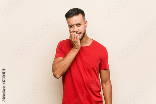 Young south-asian man biting fingernails, nervous and very anxious.