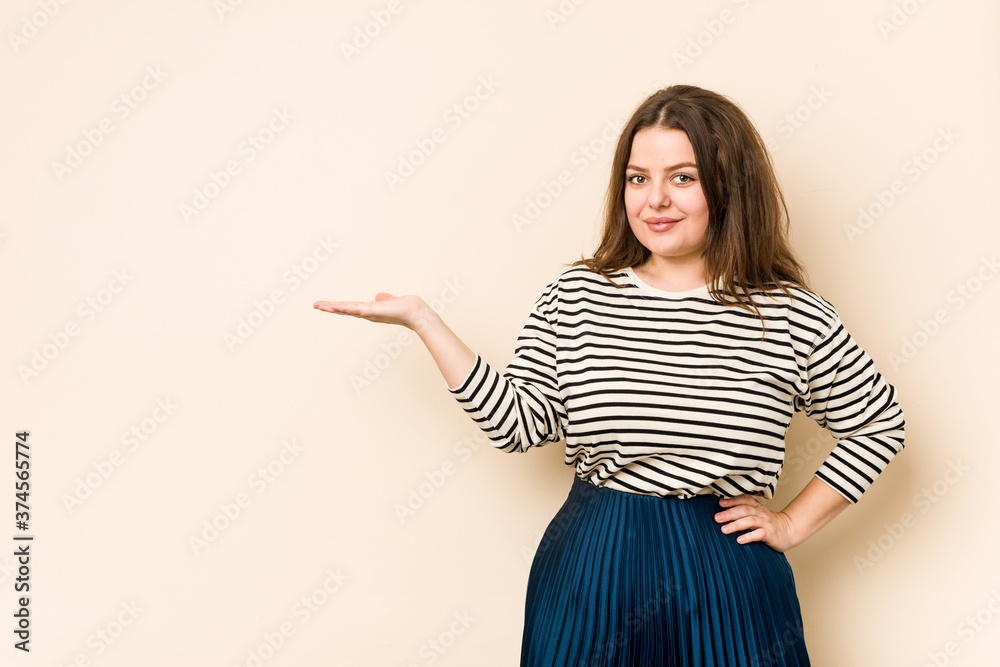 Young curvy woman showing a copy space on a palm and holding another hand on waist. Young curvy woman showing a copy space on a palm and holding another hand on waist.